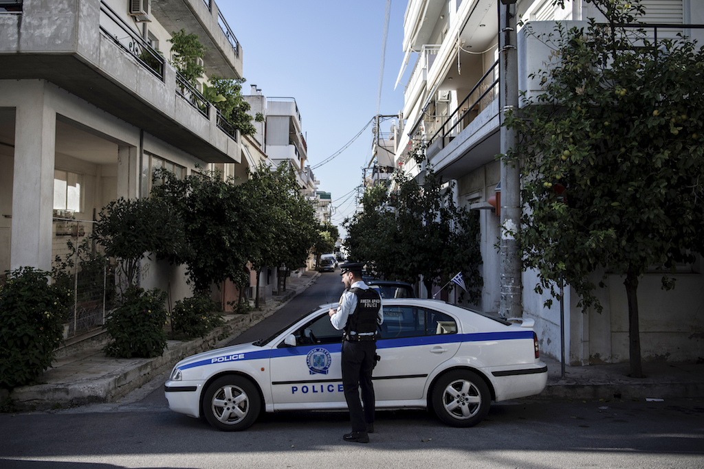 Greek police block the road as investigators inspect the scene