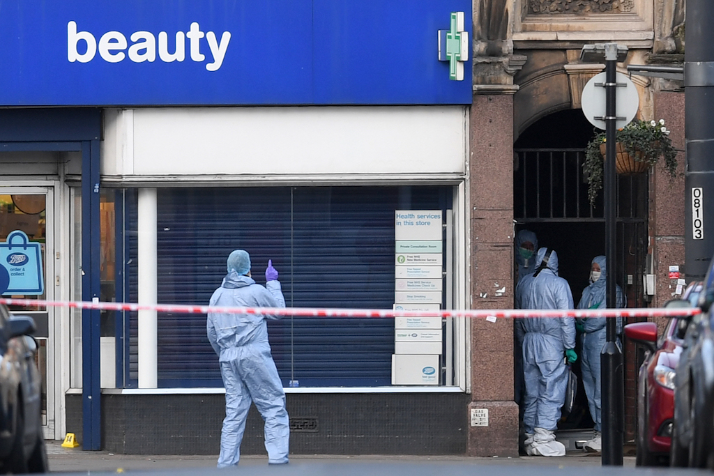 Police forensic officers work outside a store after a man was shot dead by police following reports he had stabbed two people
