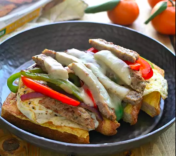 This Philly-inspired breakfast cheesesteak piles chicken sausage, peppers and cheese atop thick slices of French toast. Ingredients 6 large eggs, divided 2 tablespoons milk 4 thick slices of bread 1 (5 ounces) package Chicken Sausage Patties 1 tablespoon olive oil 1 clove garlic, minced ½ red bell pepper, thinly sliced ½ green bell pepper, thinly sliced ½ small red onion, thinly sliced 2 slices provolone cheese Salt and pepper, to taste Directions / Instructions Step 1 In a medium bowl, whisk together 2 eggs and milk; dip bread into egg mixture until fully coated. Cook French toast on a griddle or large skillet over medium heat until golden brown on both sides. Step 2 Cook sausage patties according to package instructions. Cut into strips. Step 3 In a separate skillet, heat olive oil over medium heat. Add garlic, peppers and onions and saute until browned and tender. Step 4 Add cooked sausage strips to pepper and onion mixture; top with cheese and heat until cheese is melted. Step 5 Cook remaining eggs over easy, or as desired. Step 6 Assemble cheesesteaks by layering french toast with eggs, pepper, sausage and cheese mixture. Season with salt & pepper and serve open-faced. source - cooking365coza